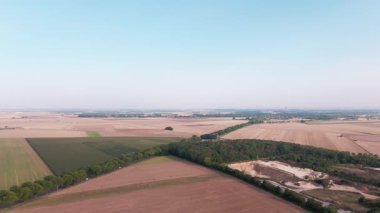 Uçsuz bucaksız tarım arazileri ve kırsal yolda giden arabanın havadan görünüşü.
