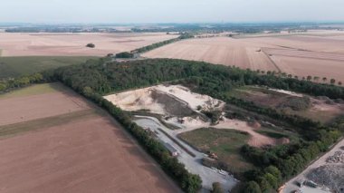 Uçsuz bucaksız tarım arazileri ve kırsal yolda giden arabanın havadan görünüşü.