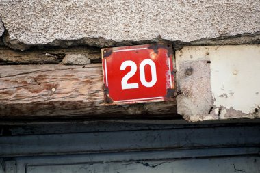 20 numaralı ev kırmızı tuğlalı duvarda, 29 numara mavi metal plakalı.