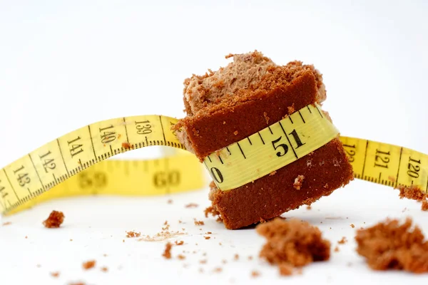 黄色の測定テープで包んだチョコレートケーキと健康的な生活コンセプトのイメージ — ストック写真