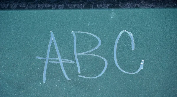 text abc written on the frozen window of a car in cold november morning