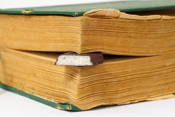 Chocolate Protein bar filled with coconut fill,between pages of an old book, education and vitality concept