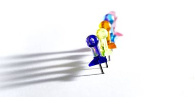 many colorful push pins on white, color concept.