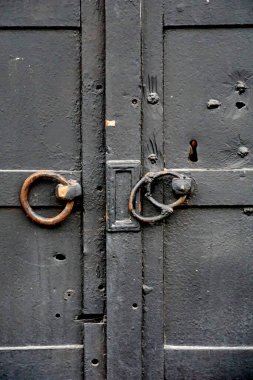 Çizgili ve perçinli dövülmüş eski bir siyah metal kapıya asma kilit. Vintage arka plan yakın plan. Kapalı geçiş ve koruma kavramı