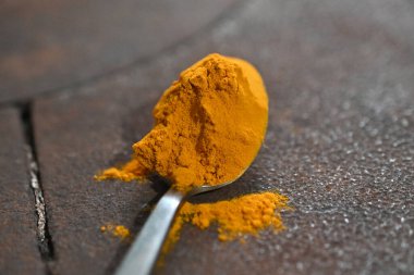 Koyu arkaplanda çay kaşığının üzerindeki şerit ya da zerdef tozu.