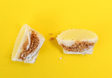 Sarı arka planda beyaz çikolata bonbonu, tatlı yemek teması.