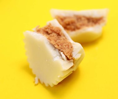 Sarı arka planda beyaz çikolata bonbonu, tatlı yemek teması.