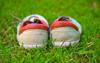 Çimenlerin üzerinde kullanılmış spor ayakkabılar, yaz ayakkabıları..