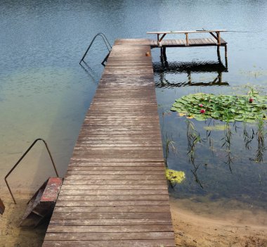 Bir köy gölünde kayıklar ve balıkçılar için ahşap iskele.