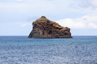 Uçsuz bucaksız mavi okyanustaki yalnız kayalık adası