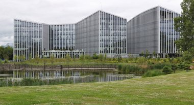 Şehir parkı gölünün kıyısındaki büyük modern ofis binası.