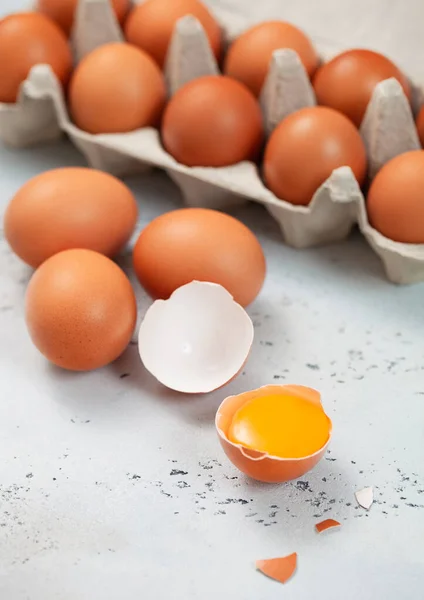 Brown eggs in classic paper tray with yolk and shell on light background