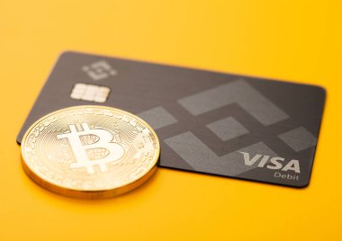 LONDON, UK - 19 Kasım 2022: sarı arka planda bitcoin ile Binance vize kredi kartı. Ticaret ve takas için kripto para platformu. Üst görünüm