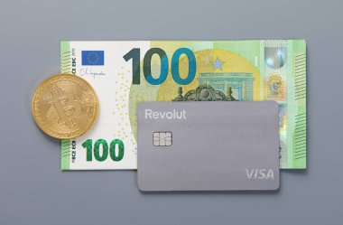 LONDON, İngiltere - 18 Kasım 2022: Revolut vizesiz erişim kartı üzerinde bitcoin ve 100 euro banknot. Kripto para birimi ve hisse senedi ticareti sanal bankacılık.