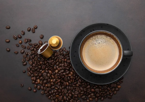 生豆と茶色のカプセルが入った磁器のカップの中の大きな黒いコーヒー — ストック写真