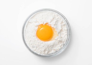 Beyaz zemin üzerinde un ve yumurta sarısı olan kase tabağı..