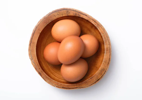 在白色背景上的木制碗盘中的褐色新鲜生鸡蛋 — 图库照片
