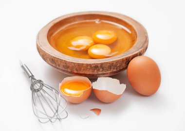 Tahta tabakta üç yumurta sarısı kabuklu ve çırpmalı.