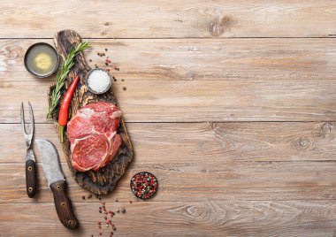 Çatal ve bıçaklı pirzola, ahşap mutfak masasında biberiyeli tuz ve biber..