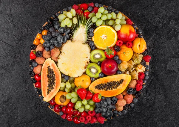 新鲜的生的夏季有机浆果和异国情调的水果在圆形的大托盘黑色厨房背景 覆盆子 猕猴桃 顶部视图 — 图库照片