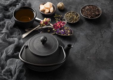 Şekerli yeşil ve siyah çay ve kaşıklı Çin çaydanlığı ve siyah arkaplanda kaşık ve kaşık.