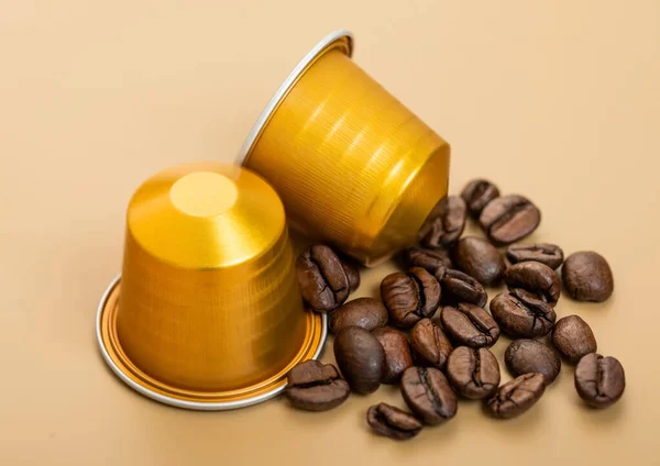 Coffee capsules with fresh raw aroma beans on beige background.Macro