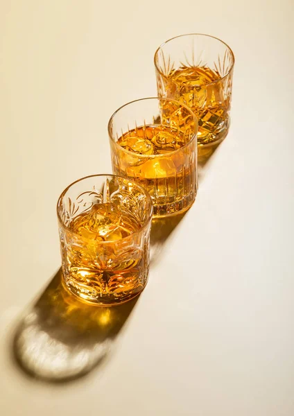 Three Whiskey Glasses Ice Cubes Golden Background Hard Light — Stock Photo, Image