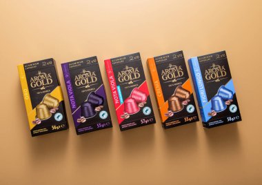 LONDON, İngiltere - 20 Aralık 2022: Kahverengi zemin üzerinde makine için çeşitli Aroma Gold alüminyum kahve kapsülleri..