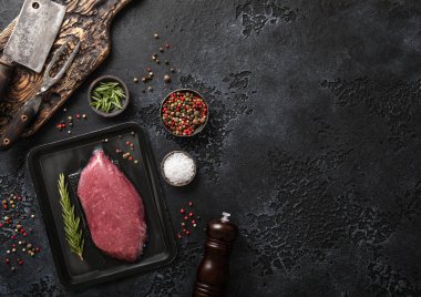 Elektrik süpürgesinde çiğ biftek, siyah arka planda biberiye, et satırı ve biber öğütücü..