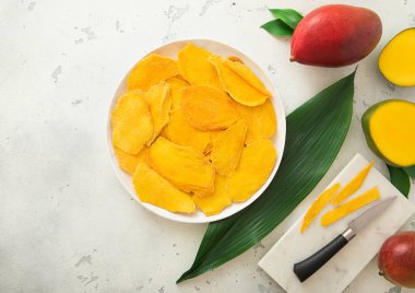 Kesme tahtası ve bıçakla kurutulmuş mango dilimli tabak..