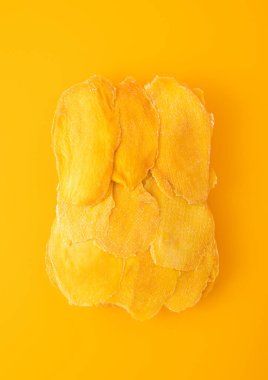 Sarı arka planda büyük kurutulmuş tatlı mango dilimleri..