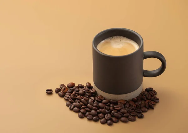コーヒー豆とともに熱いクリーム色の黒コーヒーOn Beige Board — ストック写真