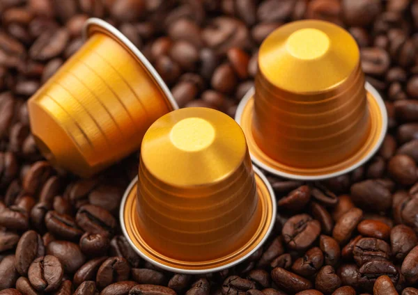 Coffee capsules for machine on fresh raw beans background.Macro