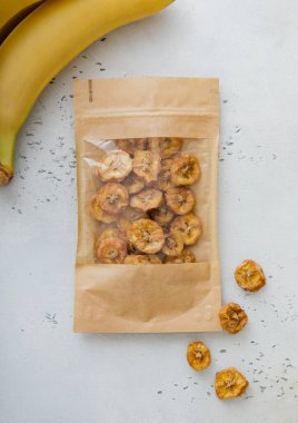 Bir paket kurutulmuş organik sağlıklı muz cipsi ve çiğ muz. Makro.