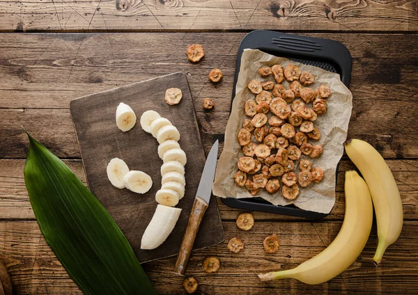 Fresh raw banana slices with dried banana chips on wooden background with green leaf.Top view