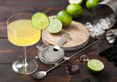 Gimlet Kamikaze kokteyli, limon dilimli, ahşap arka planda taze limonlu ve süzgeçli modern cam karışımı. Üst görünüm