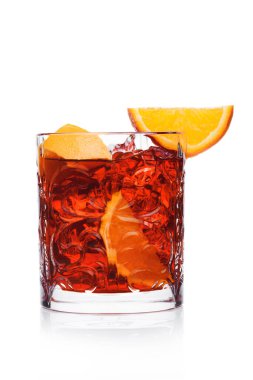 Kristal bardakta Negroni Kokteyli. Buz küpleri ve beyaz arka planda portakal dilimleri.