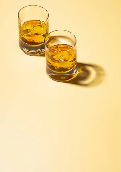 Two Whiskey Glasses Ice Cubes Golden Background Top View — Stock Photo, Image