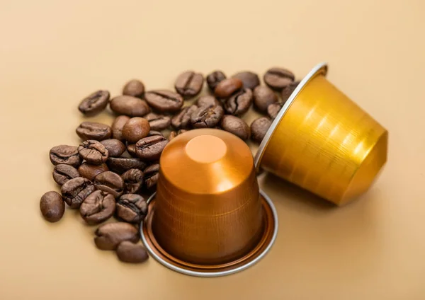 Coffee capsules with fresh raw aroma beans on beige background.Macro