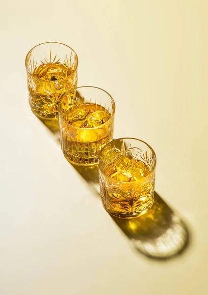 Three Whiskey Glasses Ice Cubes Golden Background — Stock Photo, Image