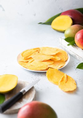 Kurumuş mango dilimli, tahta kesme tahtası ve bıçaklı bir tabak..