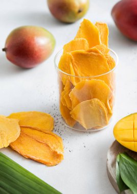 Cam kavanozda kurumuş mango parçaları ve arka planda çiğ meyveli çiğ meyve..