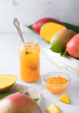 Mango reçelli reçel. Hafif arka planda kaşık ve çiğ meyveli..