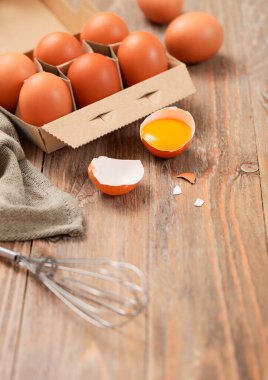 Çiğ yumurta tepsisi, un sarısı ve ahşap masa arkasında mutfak havlusu..