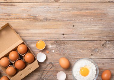 Yumurta ve un, sarısı ve mutfak havlusuyla ahşap masa üzerinde metal çırpılmış. Üst görünüm