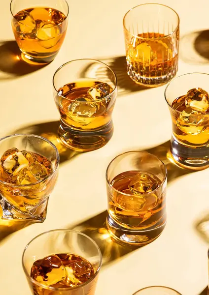 Whiskey and bourbon in luxury glasses with ice cubes on golden background.Top view.