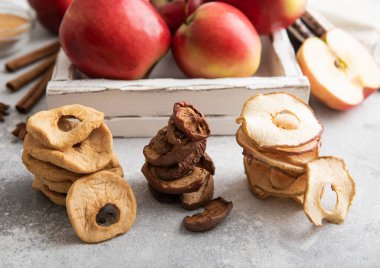 Arkaplanda çeşitli kurumuş elma dilimleri, cips ve halkalar var.