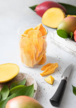 Cam kavanozda kurutulmuş mango, çiğ meyve ve çakı var..