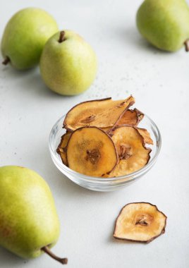 Kahverengi armut parçaları cam kasede dilimler yeşil armutlar ışık masasında.