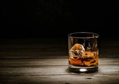 Ahşap zeminde buz küpleri olan klasik viski bardağı..